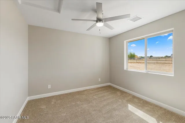 an empty room with a window and ceiling fan