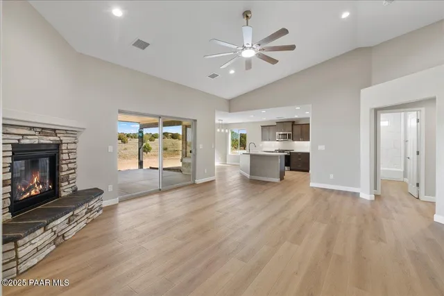 an empty room with windows fireplace and wooden floor