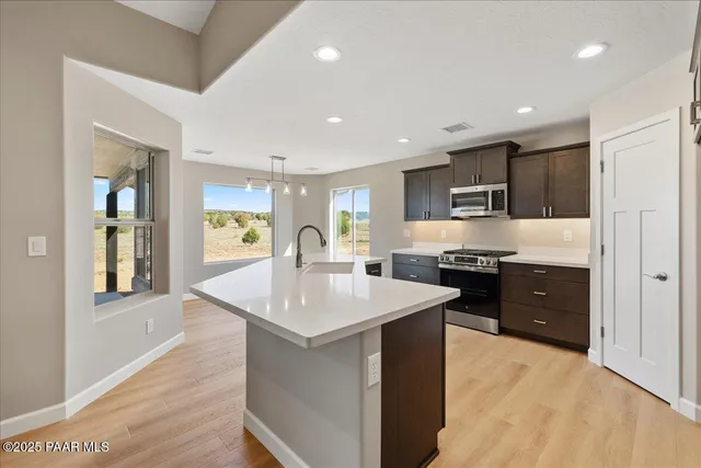 a large kitchen with stainless steel appliances a sink dishwasher stove and wooden cabinets