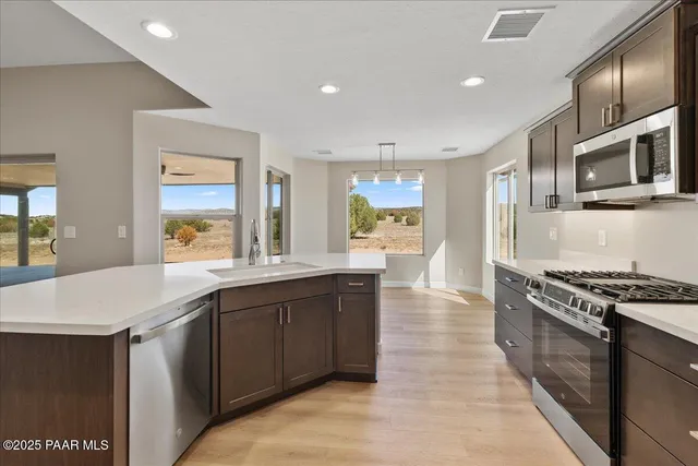 a kitchen with stainless steel appliances granite countertop a stove a sink and a microwave