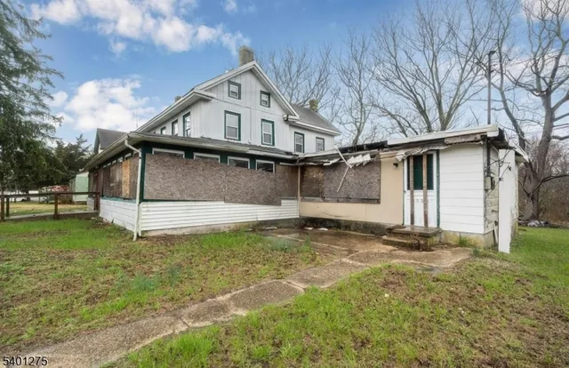 a view of a white house that has a small yard and large trees