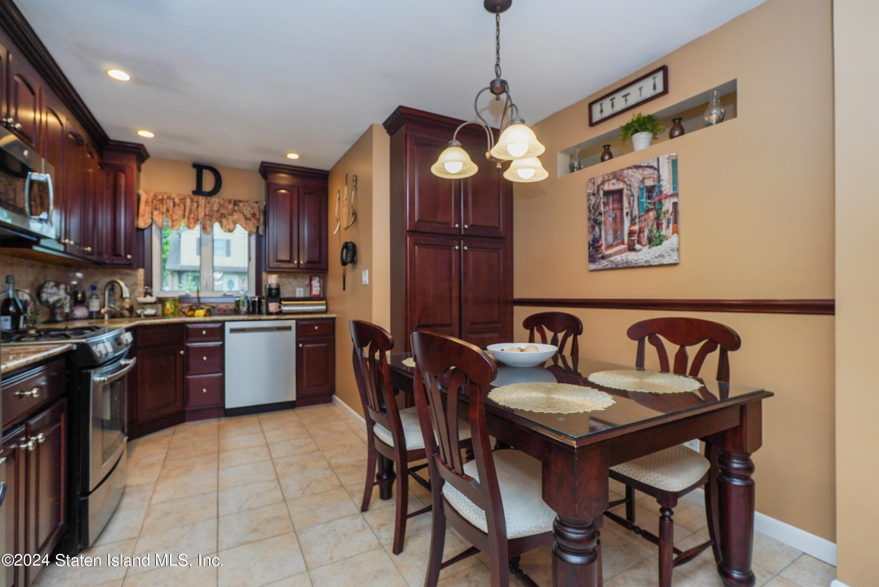 50 Ridgecrest Avenue Staten Island, NY 10312 - Photo 11 of 34 a kitchen with stainless steel appliances granite countertop a stove a sink dishwasher a dining table and chairs with wooden floor