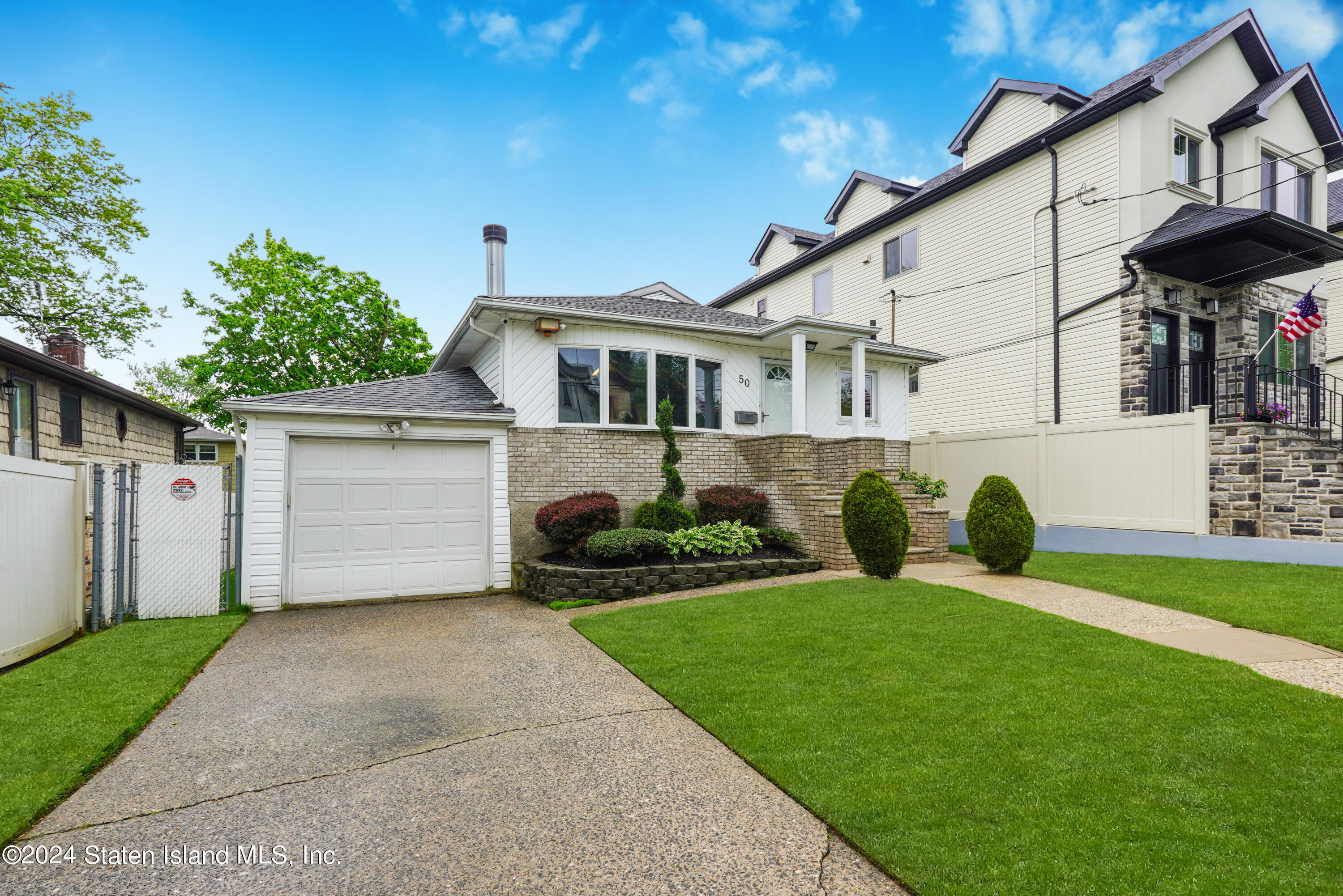 50 Ridgecrest Avenue Staten Island, NY 10312 - Photo 3 of 34 a front view of a house with a garden and plants