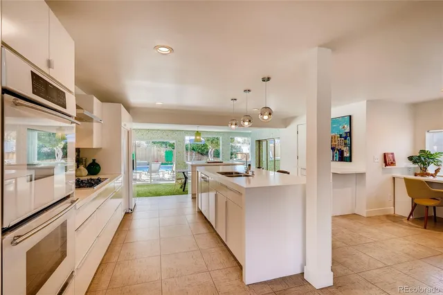 a large white kitchen with a large window and furniture