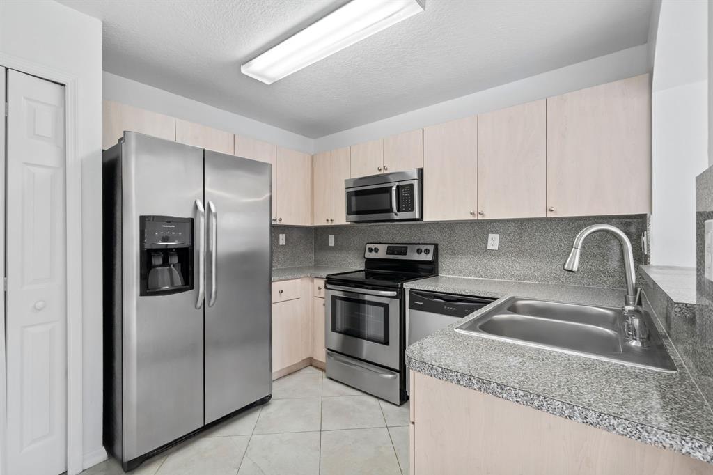 717 Southwest 107th Avenue, Unit 2203 Pembroke Pines, FL 33025 - Photo 8 of 22 a kitchen with stainless steel appliances granite countertop a refrigerator a stove a sink and a granite counter tops
