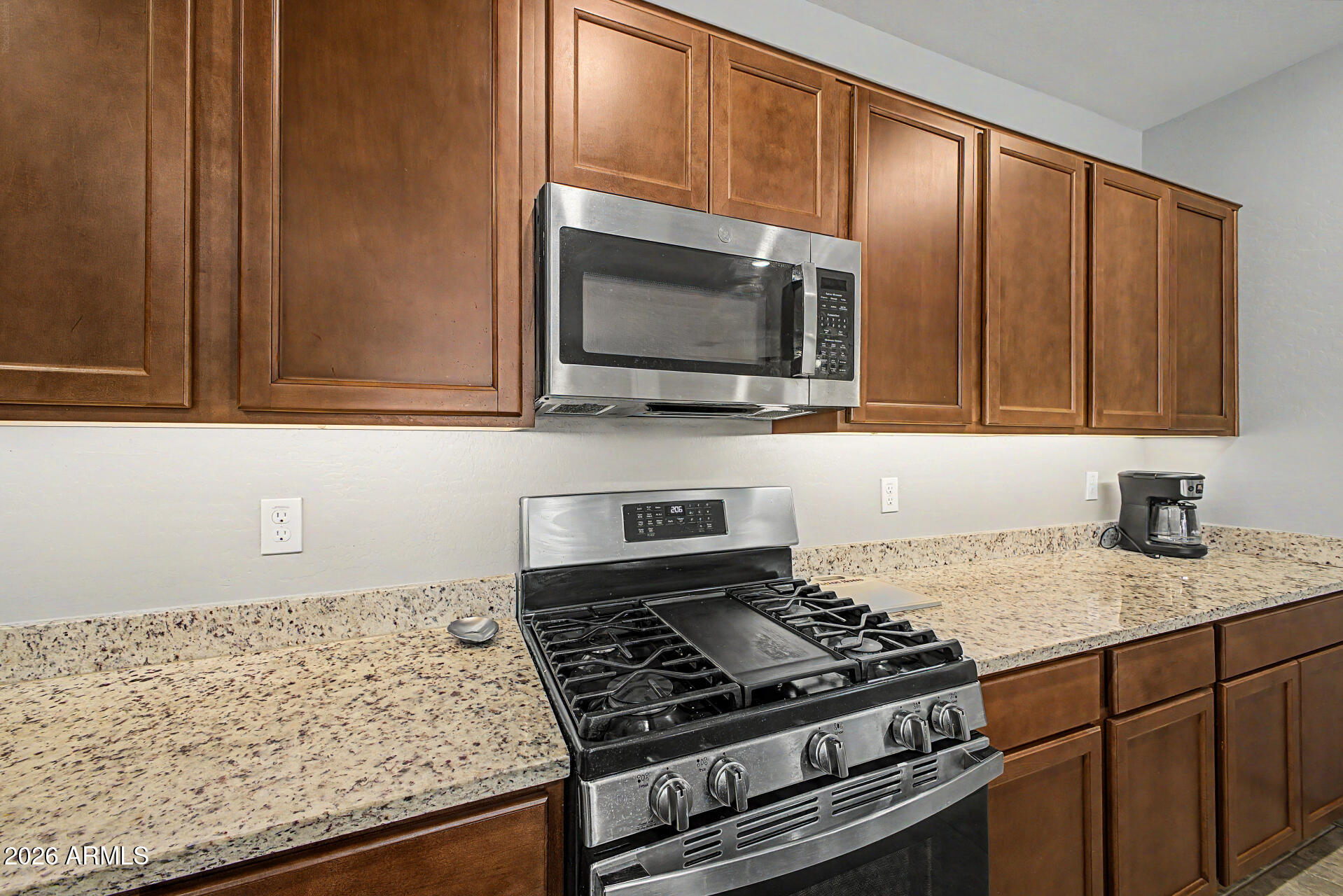 15088 West Garfield Street Goodyear, AZ 85338 - Photo 11 of 31 a kitchen with granite countertop a stove and a microwave