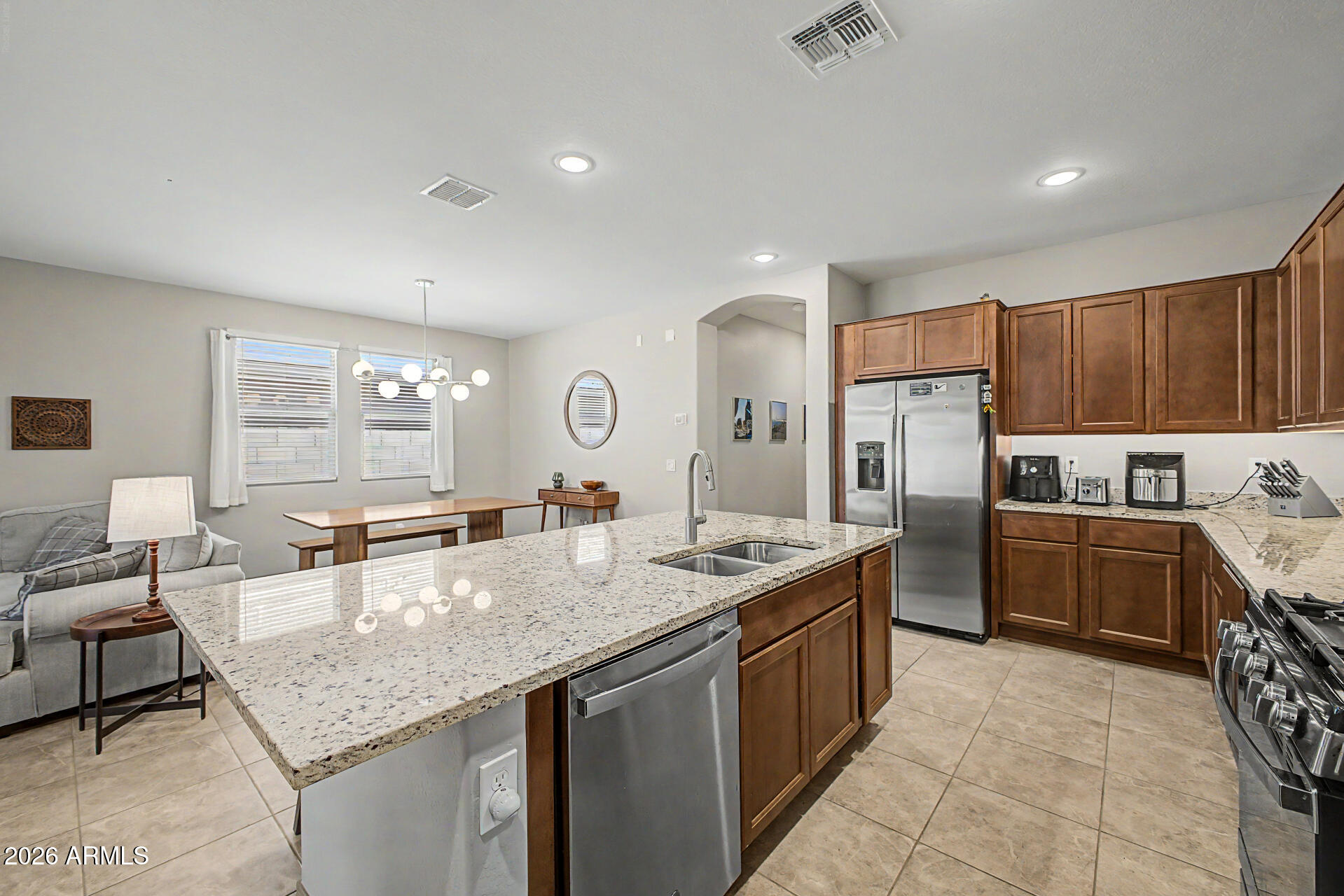 15088 West Garfield Street Goodyear, AZ 85338 - Photo 9 of 31 a kitchen with granite countertop a sink a counter top space and stainless steel appliances