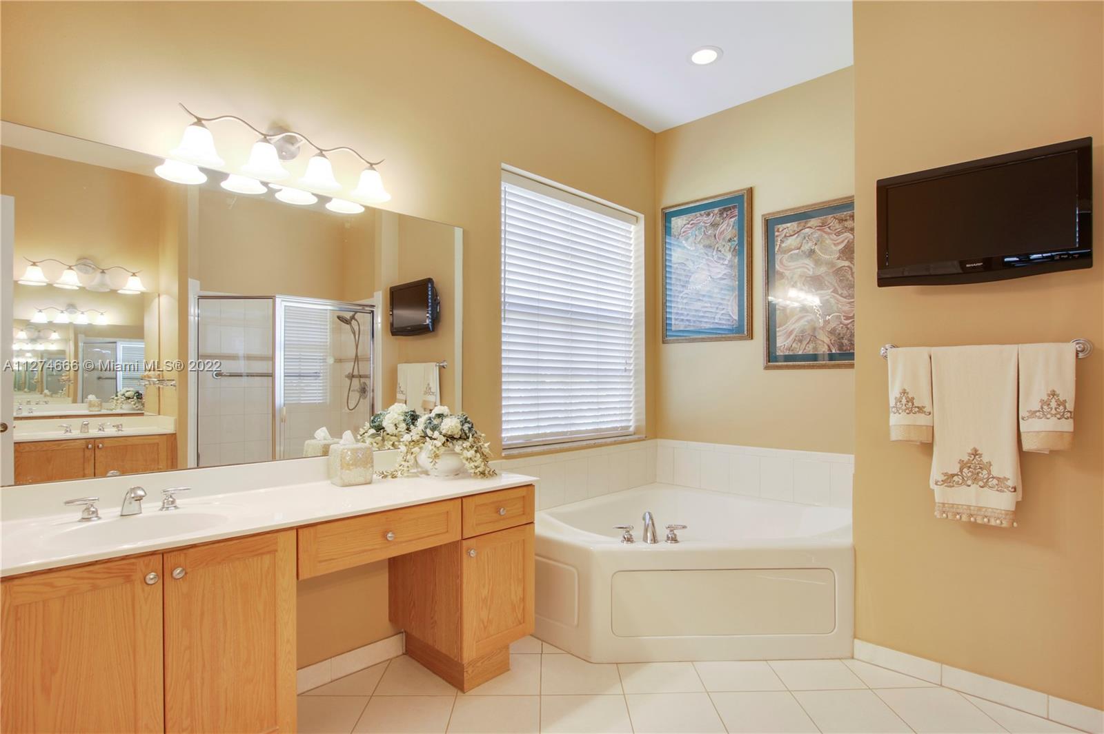 116 Via Rosina Jupiter, FL 33458 - Photo 15 of 32 a bathroom with a tub a sink double vanity and a large mirror