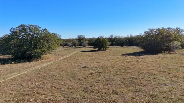 a view of a dirt field with trees in the background