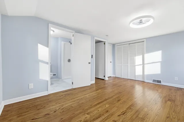 a view of an empty room with wooden floor and a window