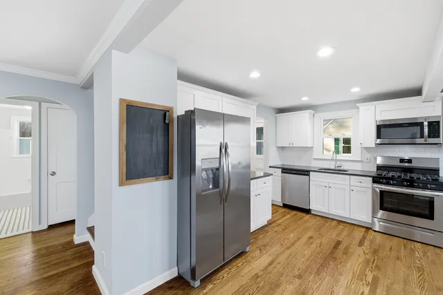 a kitchen with a refrigerator stainless steel appliances wooden floor and cabinets