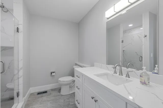 a bathroom with a sink toilet vanity and shower