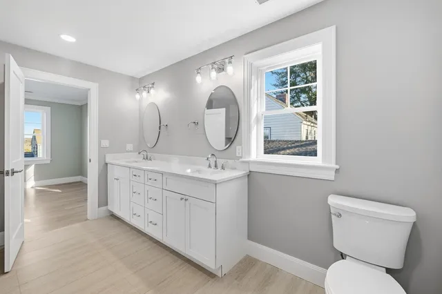 a spacious bathroom with a granite countertop toilet a sink and a mirror