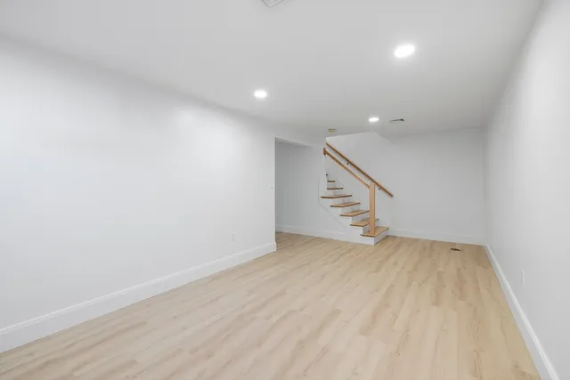 a view of an empty room with wooden floor and stairs