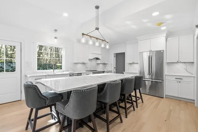 a kitchen with stainless steel appliances granite countertop a dining table chairs stove refrigerator and cabinets