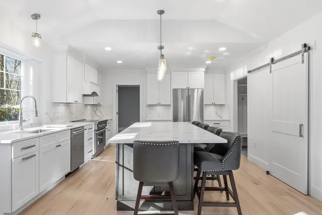 a large kitchen with a table chairs refrigerator and cabinets