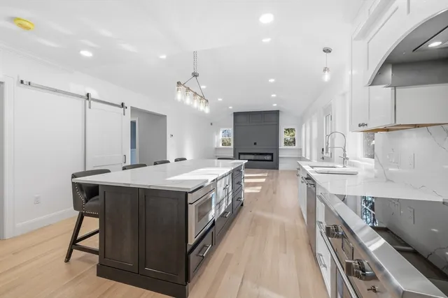 a large kitchen with a large counter top a sink stainless steel appliances and cabinets