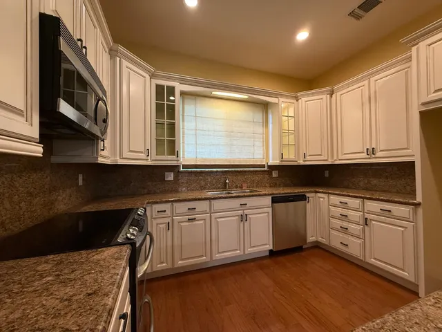 a kitchen with stainless steel appliances granite countertop a stove a sink and a microwave