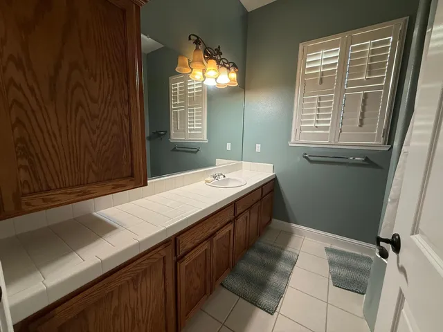 a bathroom with a granite countertop sink a mirror and a bathtub
