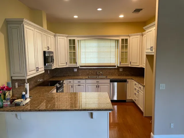 a kitchen with kitchen island granite countertop a sink stove and cabinets