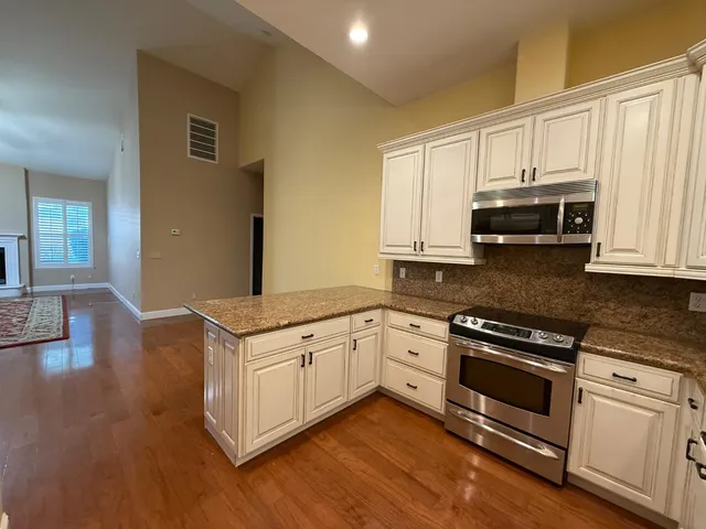 a kitchen with granite countertop white cabinets and appliances