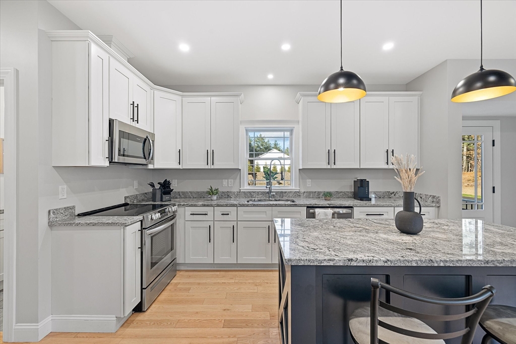 245 Brookside Road Athol, MA 01331 - Photo 5 of 27 a kitchen with stainless steel appliances granite countertop a stove a sink a microwave a refrigerator and white cabinets with wooden floor