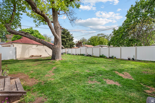88 East C Street Springville, UT 84663 - Photo 30 of 32 Expansive green lawn featuring a mature shade tree, a white privacy fence, and a detached structure with a red roof