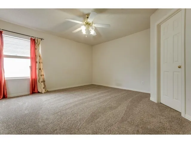 a view of an empty room and chandelier fan