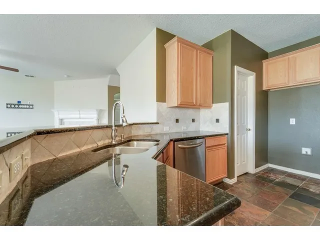 a kitchen with kitchen island granite countertop a sink cabinets and granite counter top