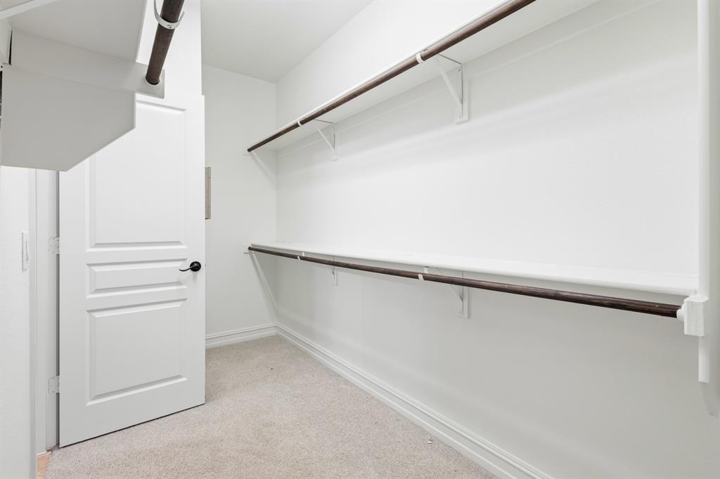 1995 Verde Court Allen, TX 75013 - Photo 12 of 30 Spacious closet featuring two levels of hanging rods, soft neutral carpeting, crisp white walls, and a multi-panel door with a matte black knob