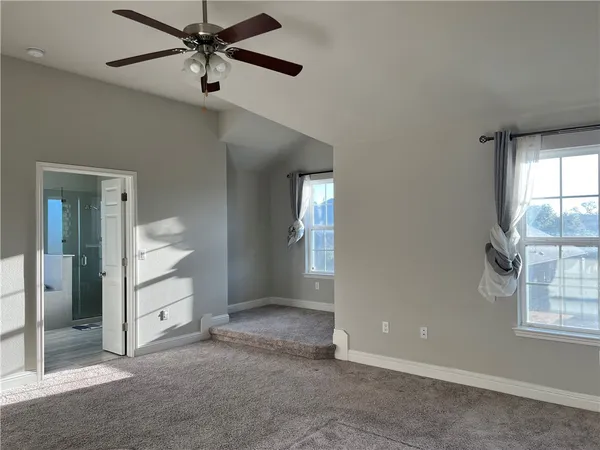 an empty room with windows and fan