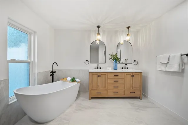 a spacious bathroom with a double vanity sink a mirror a bathtub and
