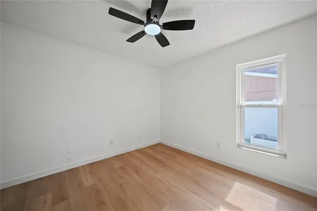an empty room with a window and a fan