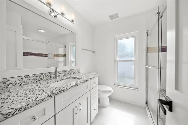 a bathroom with a granite countertop sink a toilet and a shower