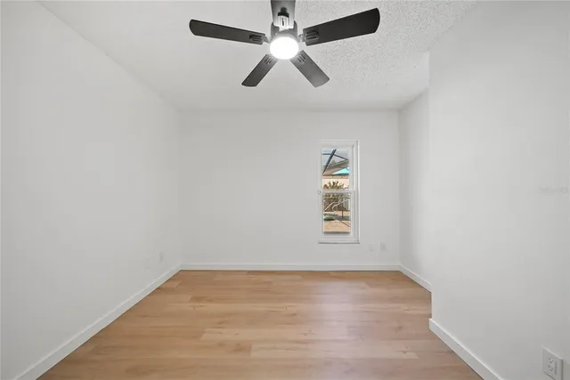 an empty room with ceiling fan and window