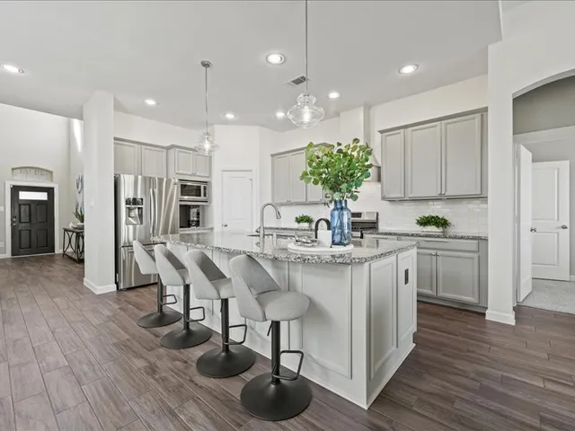 a kitchen with stainless steel appliances kitchen island granite countertop a wooden floors and white cabinets