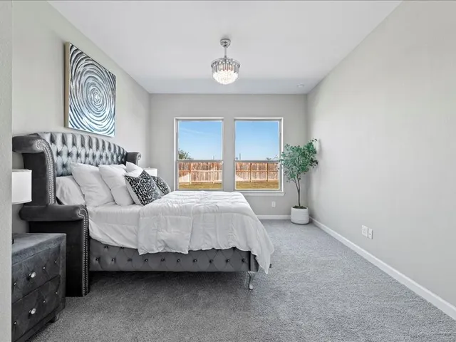 a spacious bedroom with a bed a dresser and next to a window