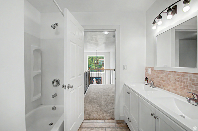 12645 East Cedar Ridge Drive Fairview, UT 84629 - Photo 24 of 34 White bathroom vanity with dual integrated sinks, chrome fixtures, and a neutral tile backsplash