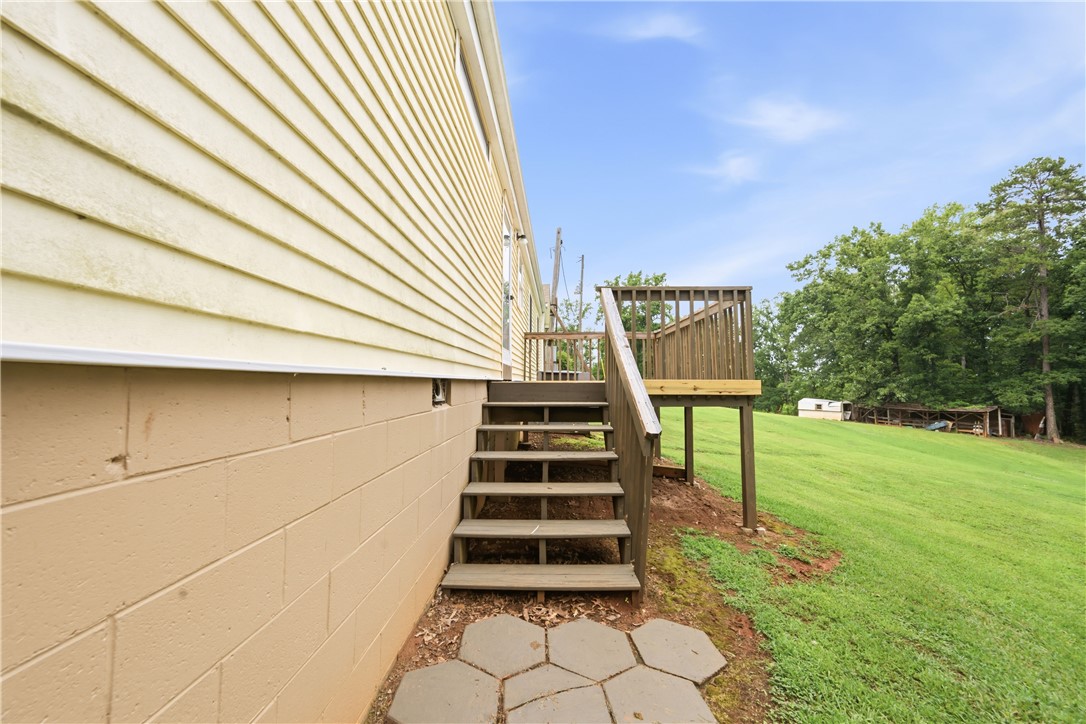 942 Chambers Hill Road Seneca, SC 29672 - Photo 32 of 38 A wooden deck and steps extend to a spacious, verdant yard, offering ample outdoor enjoyment.