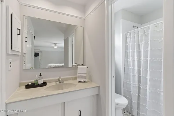 a bathroom with a granite countertop sink toilet a mirror a vanity and shower
