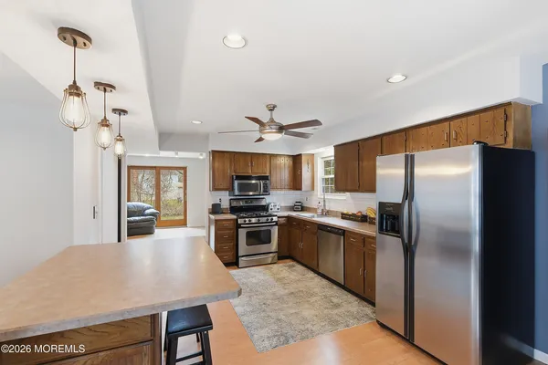 a kitchen with stainless steel appliances granite countertop a refrigerator a stove a sink a dining table and chairs with wooden floor
