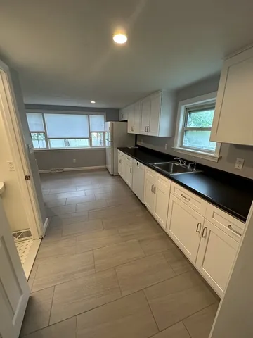 a large white kitchen with stainless steel appliances a sink dishwasher a stove a microwave and a refrigerator