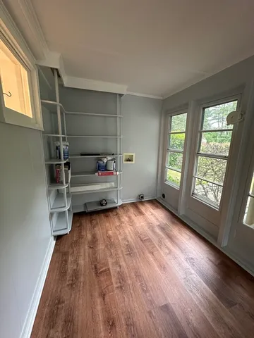 a view of an empty room with wooden floor and a window