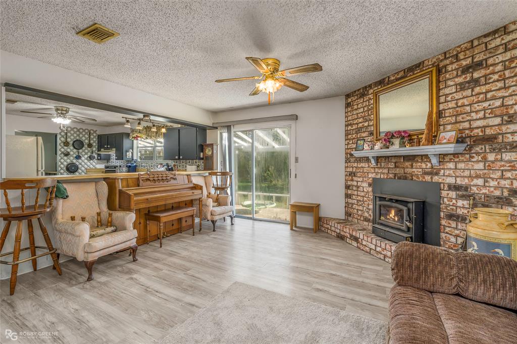 251 Tom Murphy Road Jamestown, LA 71045 - Photo 15 of 40 Living room featuring ceiling fan, light wood-type flooring, a textured ceiling, and a wood stove
