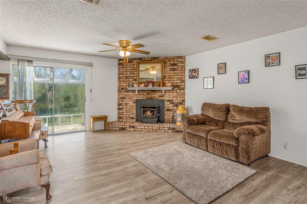 251 Tom Murphy Road Jamestown, LA 71045 - Photo 16 of 40 Living room with light wood-style flooring, a ceiling fan, a textured ceiling, and a brick fireplace