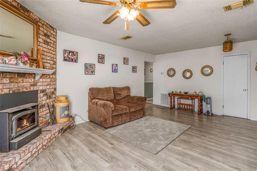 251 Tom Murphy Road Jamestown, LA 71045 - Photo 17 of 40 Living area featuring a textured ceiling, ceiling fan, light wood finished floors, and a wood stove