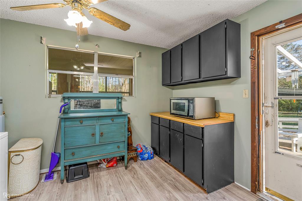 251 Tom Murphy Road Jamestown, LA 71045 - Photo 25 of 40 Kitchen featuring a textured ceiling, light wood finished floors, stainless steel microwave, dark cabinets, and a ceiling fan