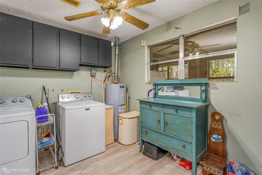 251 Tom Murphy Road Jamestown, LA 71045 - Photo 26 of 40 Laundry room with cabinet space, light wood-style floors, a textured ceiling, electric water heater, and a ceiling fan
