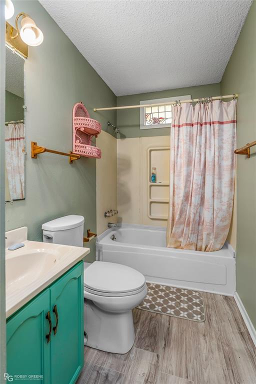 251 Tom Murphy Road Jamestown, LA 71045 - Photo 37 of 40 Bathroom with vanity, shower / bath combo with shower curtain, a textured ceiling, and light wood-style flooring