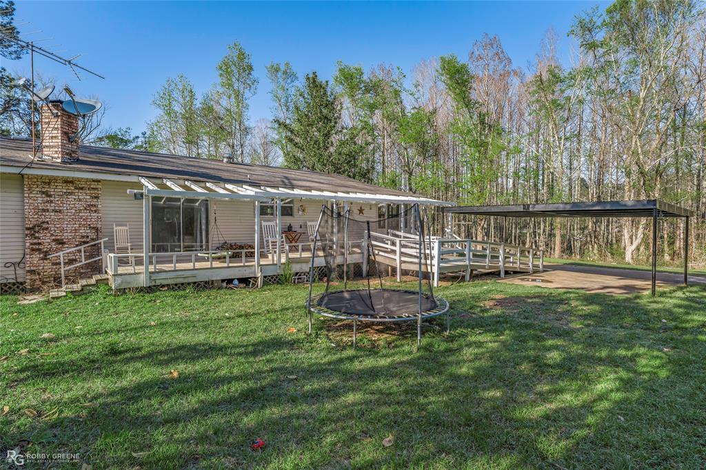 251 Tom Murphy Road Jamestown, LA 71045 - Photo 5 of 40 View of green lawn featuring a deck and a trampoline